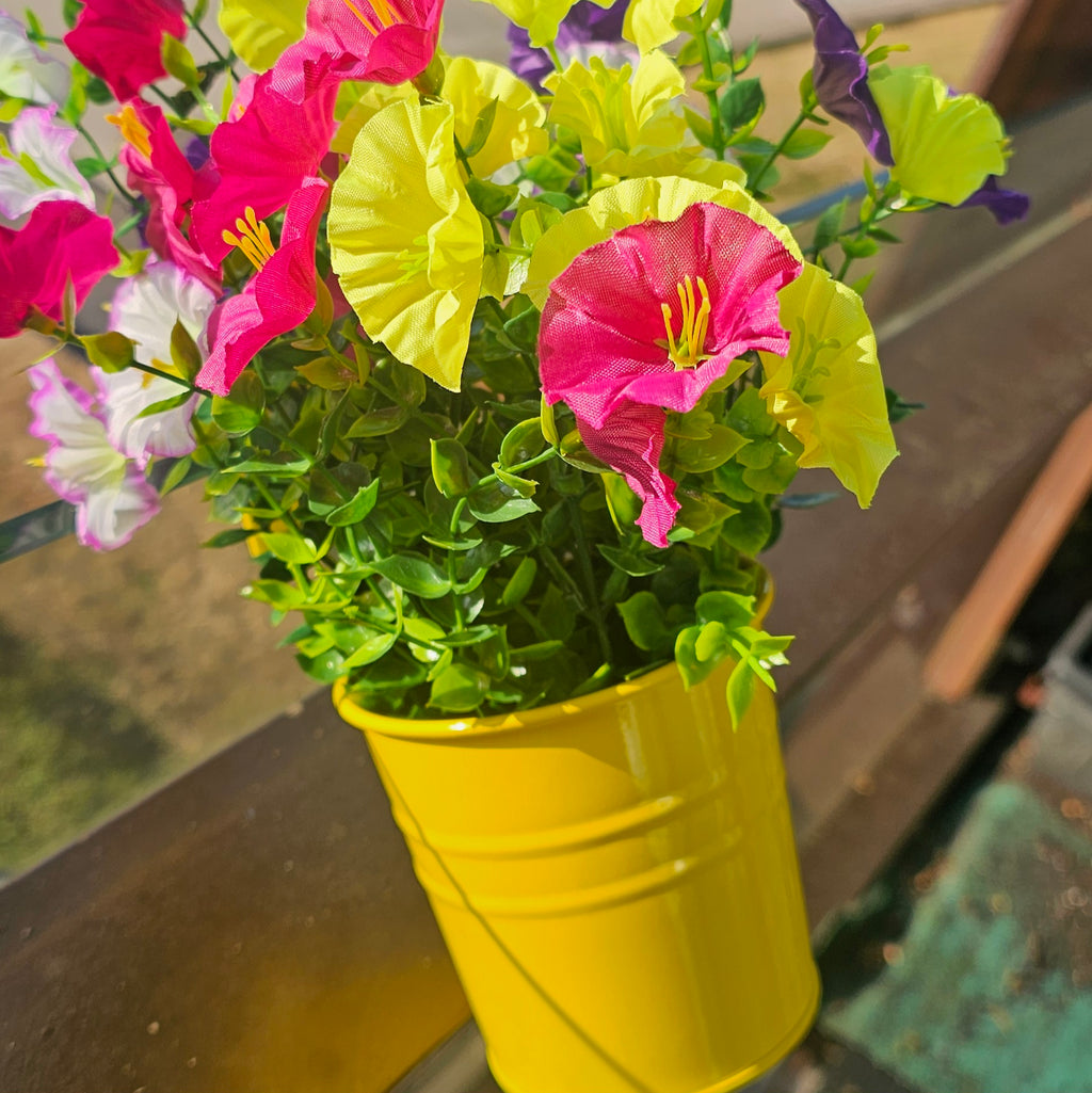 Gelber Metall-Blumentopf mit Blumen